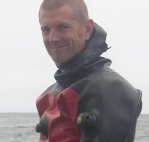 Sean Sheldrake wearing a wetsuit and looking at the camera.