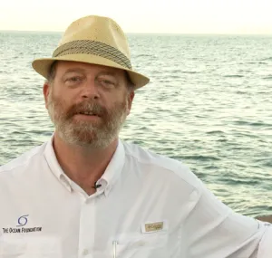 Mark J. Spalding standing with ocean water behind him. 