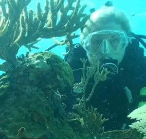 Laurie Penland diving with a corals next to her.