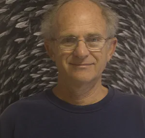 Wayne Levin smiling at camera with one of his photos in background.