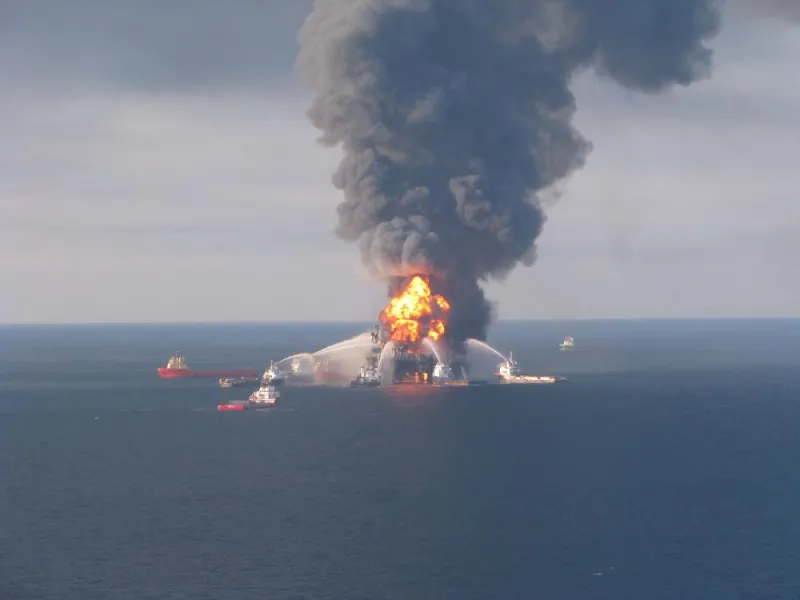 Fire fighting ships surround the burning Deepwater Horizon oil rig, shooting water at it to put out the flames.