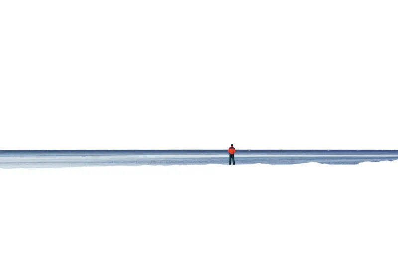 A white Antarctic landscape with John Weller standing away from the camera in the distance.