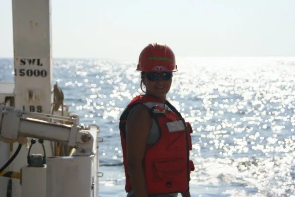 a woman works on a ship in a hard hat and vest