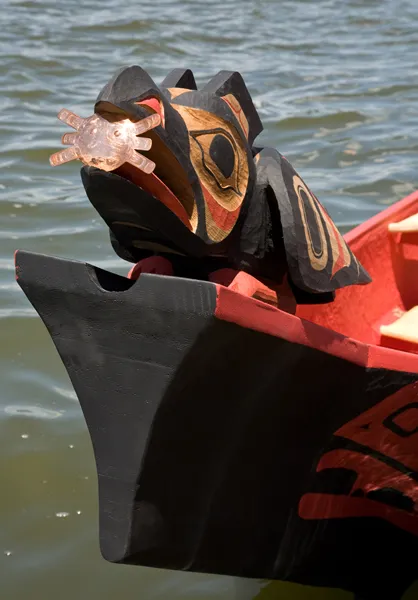 With the sun in its beak, the canoe’s raven figurehead points the way.