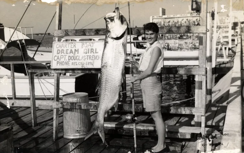 a young woman stands by a fish equal to her size