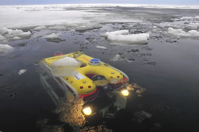 A yellow remotely operated underwater vehicle, or ROV, at the surface of the water. 