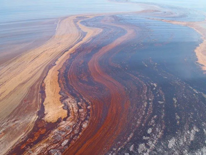 a ripple of rust colored oil in the ocean
