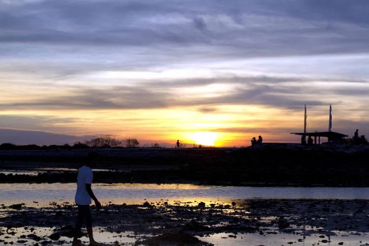 The sun sets over Sanur in Bali, Indonesia during low tide.