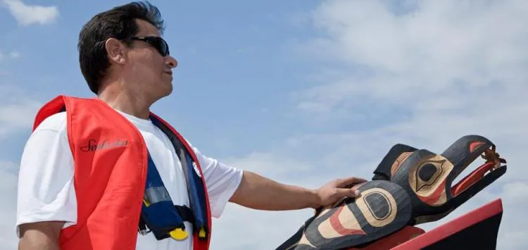 Master carver Douglas Chilton rides in the Raven Spirit canoe at its ceremonial launch.