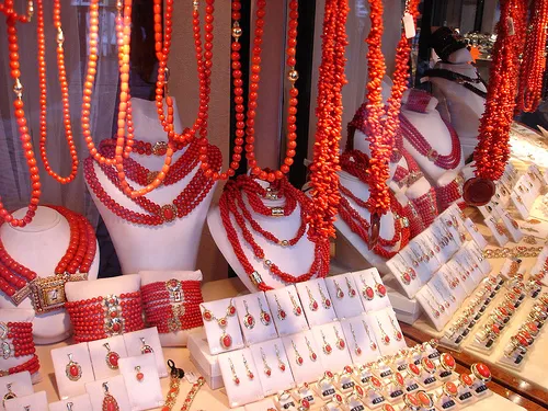 a display case of red coral jewelry containing necklaces, earrings, bracelets, and rings