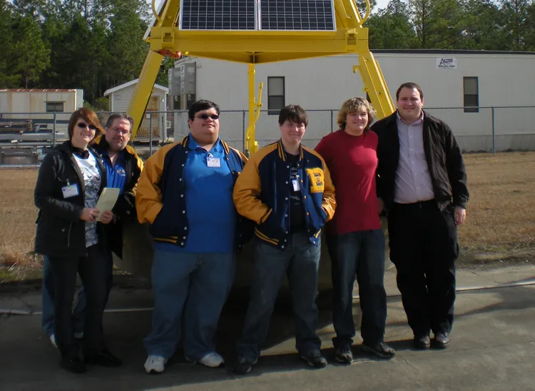 Students studying climate change pose for a photo at a NOAA facility.