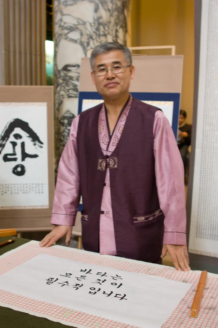 Calligrapher Myoung-Won Kwon poses with a work that has an ocean-themed message.