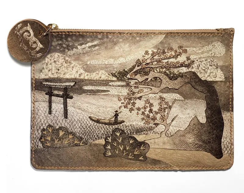A clutch bag made from fish skin with a detailed design of a landscape.