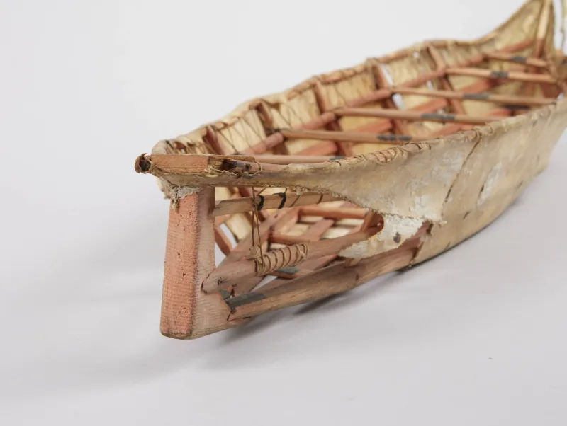 the covering of a skin boat is broken away revealing the frame