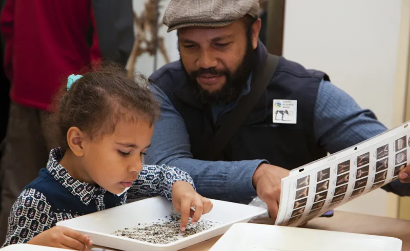 An adult and child visitor participate in an activity at the Natural History Museum 