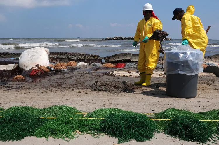 Health, Safety, and Environment (HSE) workers contracted by BP clean up oil on the beach in Port Fourchon, La. May 23, 2010.