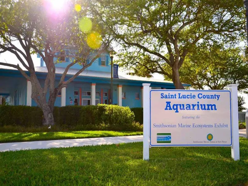 the front of a building among trees and a sign