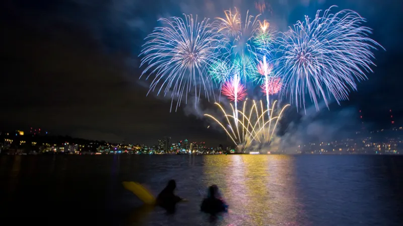 Colorful fireworks go off over the water. 