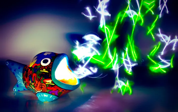 A light painted image of a hand-painted ceramic fish with light emitting from its mouth