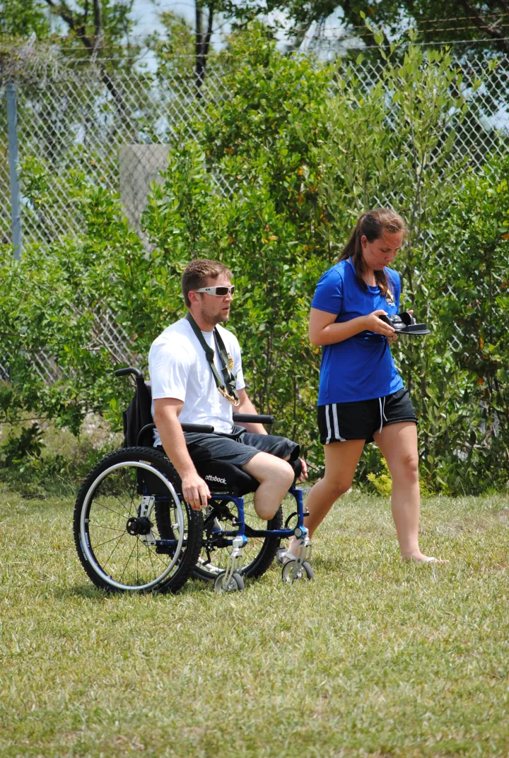 A wounded warrior and a SCUBAnaut practice compass navigation in a field. 
