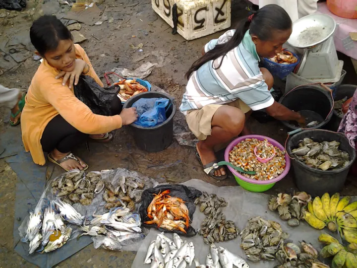 Two young women with seafood on a tarp