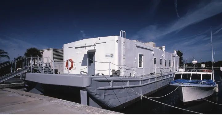 A small ship with a building on it  
