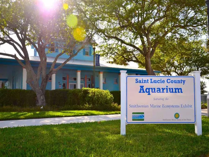 the front of a building among trees and a sign