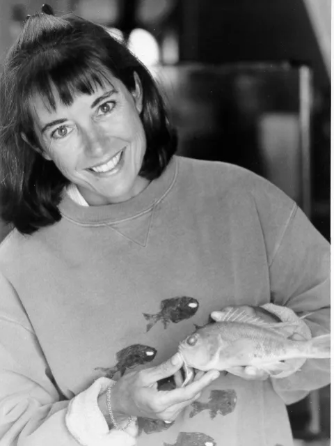 a young female researcher holds a fish