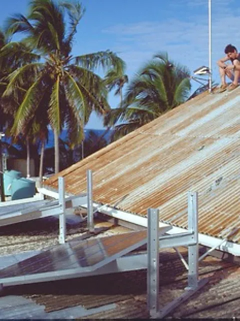 a man sits on top of a roof covered in solar panels